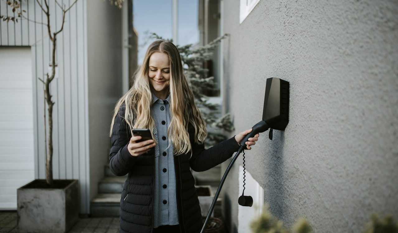Kvinne bruker Easee hjemmelader montert til husvegg